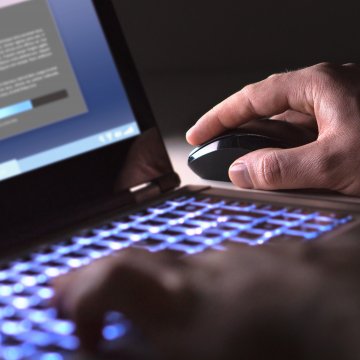 Image of hand on mouse installing a program on a laptop